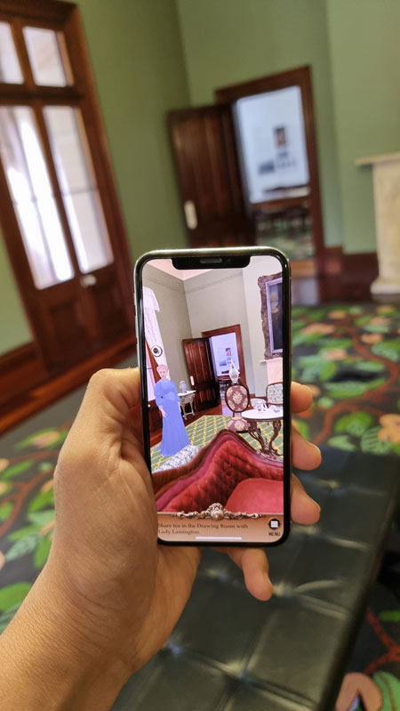 A person holding a mobile phone using the Old Government House, Brisbane, Augmented Reality (AR) touring app.