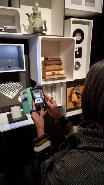 Visitor using a phone to activate AR content connected to exhibition objects.