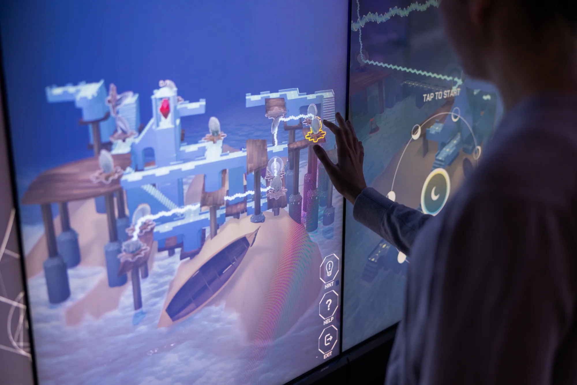 Visitor touching an EarthTime puzzle on The Cube's large screen display.